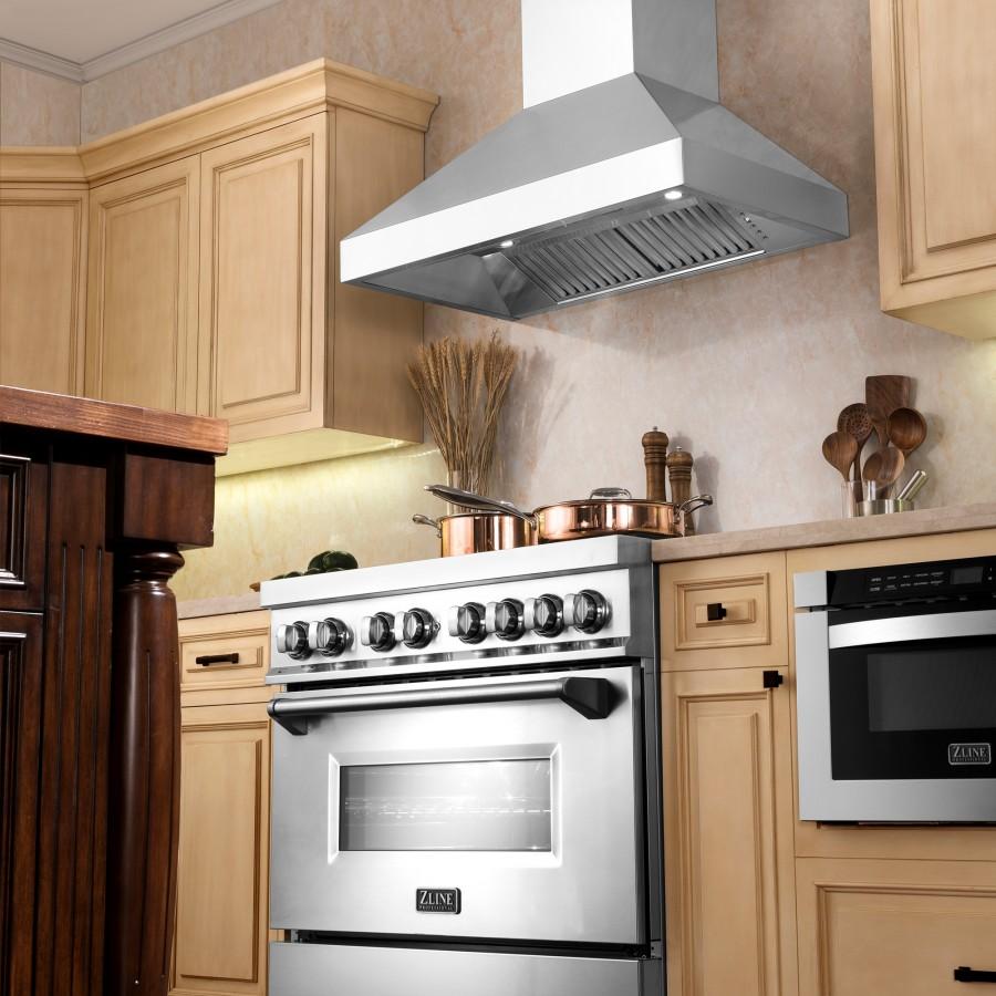 Stainless steel wall range hood mounted above a gas cooktop in a kitchen