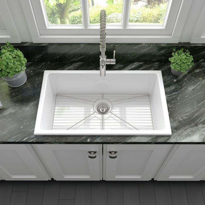 White fireclay single-bowl sink with installed faucet and visible drain opening
