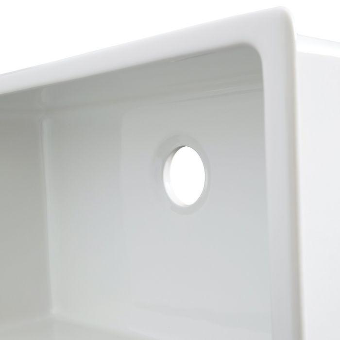 White fireclay sink side view showing round drain hole and smooth interior