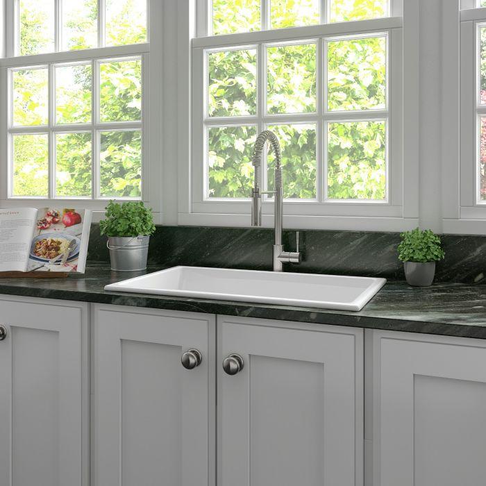 Installed white single-bowl kitchen sink with chrome faucet on dark countertop.
