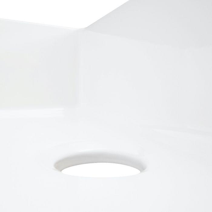 White fireclay sink drain opening close-up on smooth basin surface