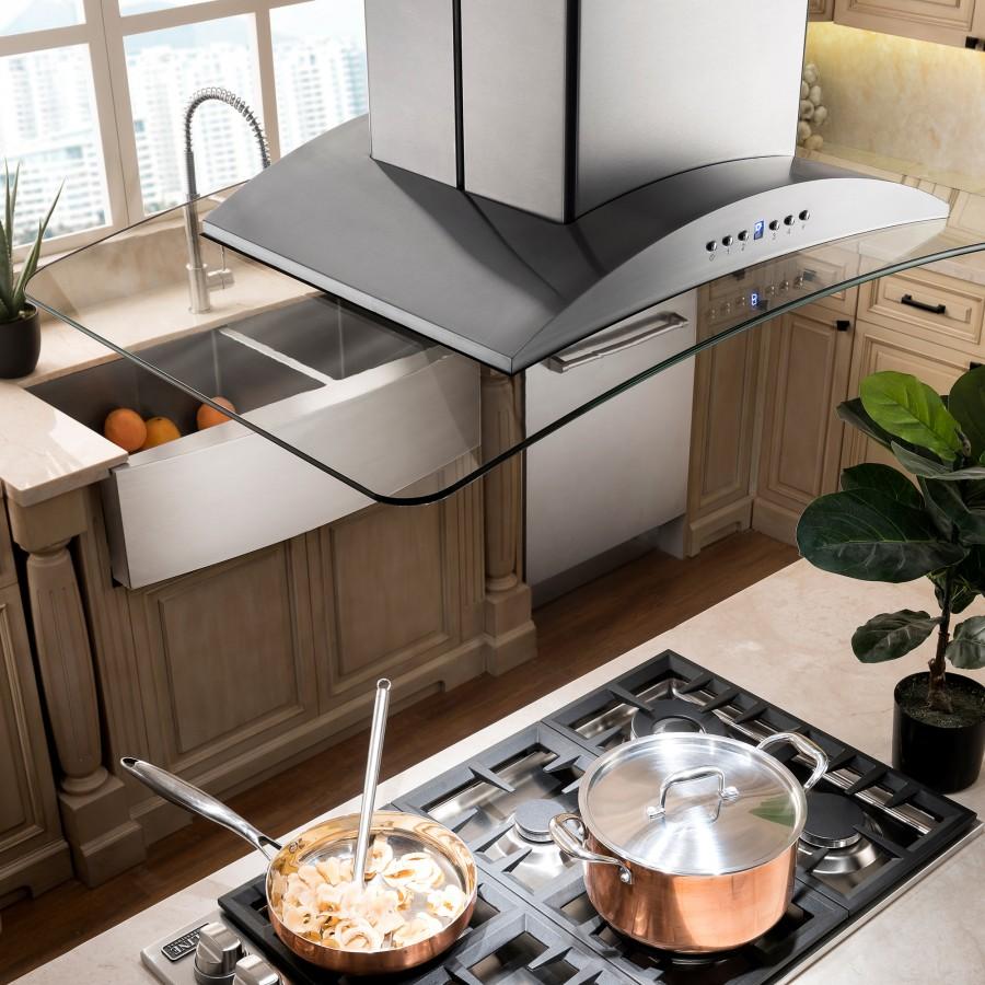 Island range hood over cooktop with tall chimney stack and curved glass shield