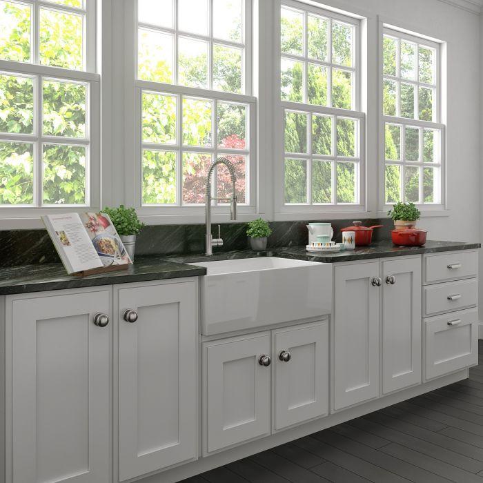 White apron-front single-bowl farmhouse kitchen sink with deck-mounted faucet