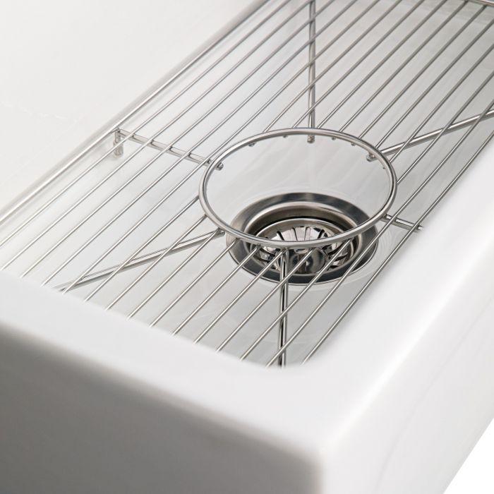 White fireclay single-bowl sink showing stainless drain strainer and wire bottom grid