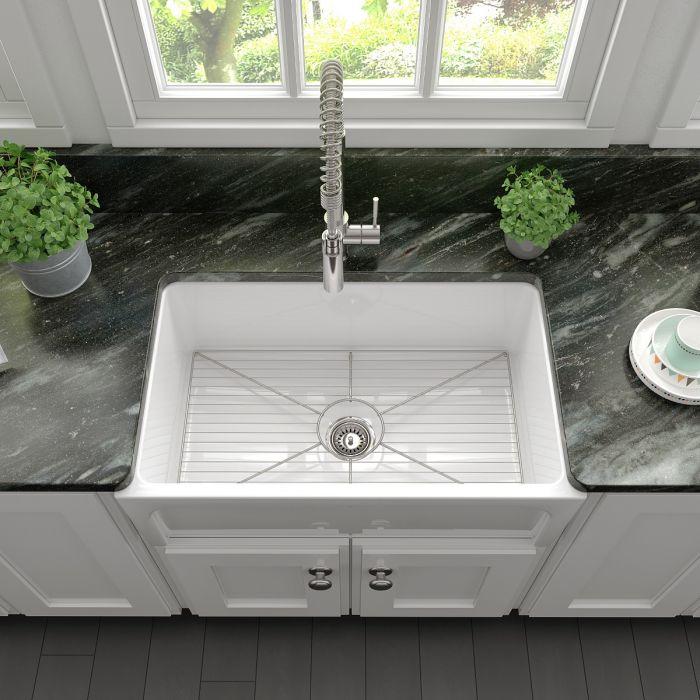 White apron-front kitchen sink with bottom grid and centered drain opening