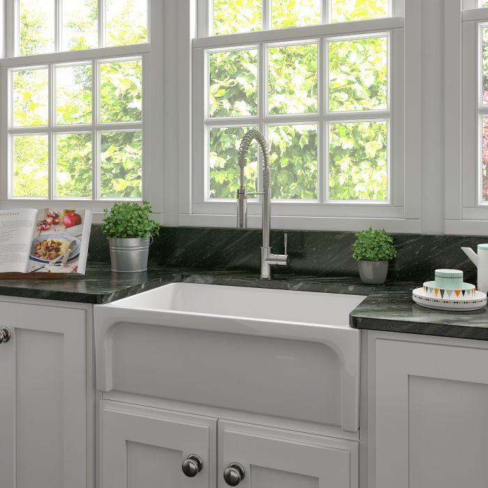 White farmhouse apron-front single-bowl fireclay kitchen sink with chrome faucet, empty basin