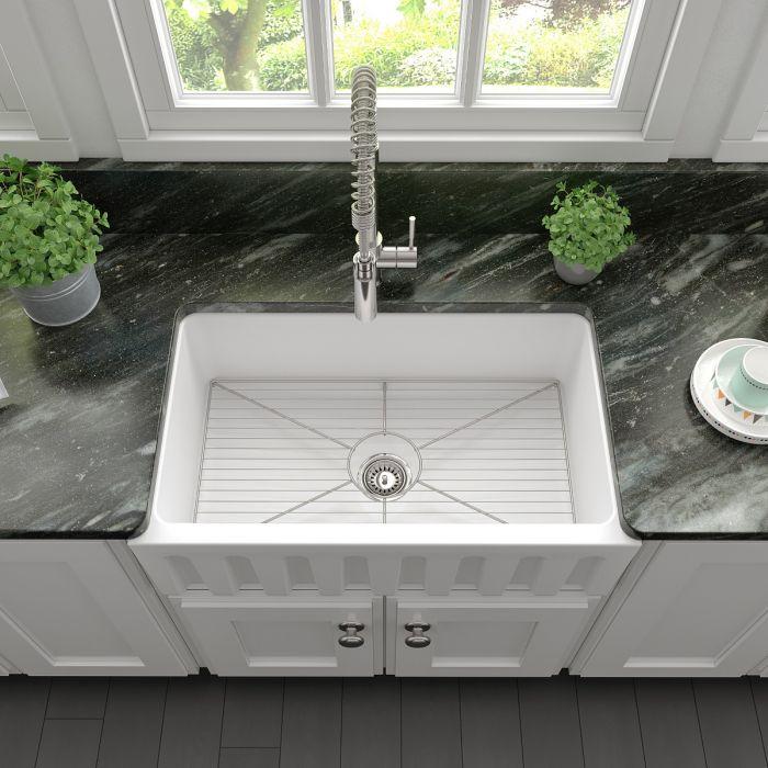 White apron-front single-bowl sink with bottom grid and central drain in kitchen
