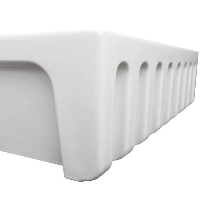 Close-up of white matte apron-front sink corner with vertical apron cutouts