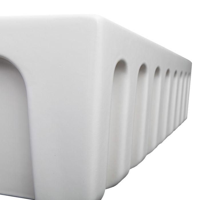 Close-up of white matte apron-front fireclay sink rim and ribbed side profile