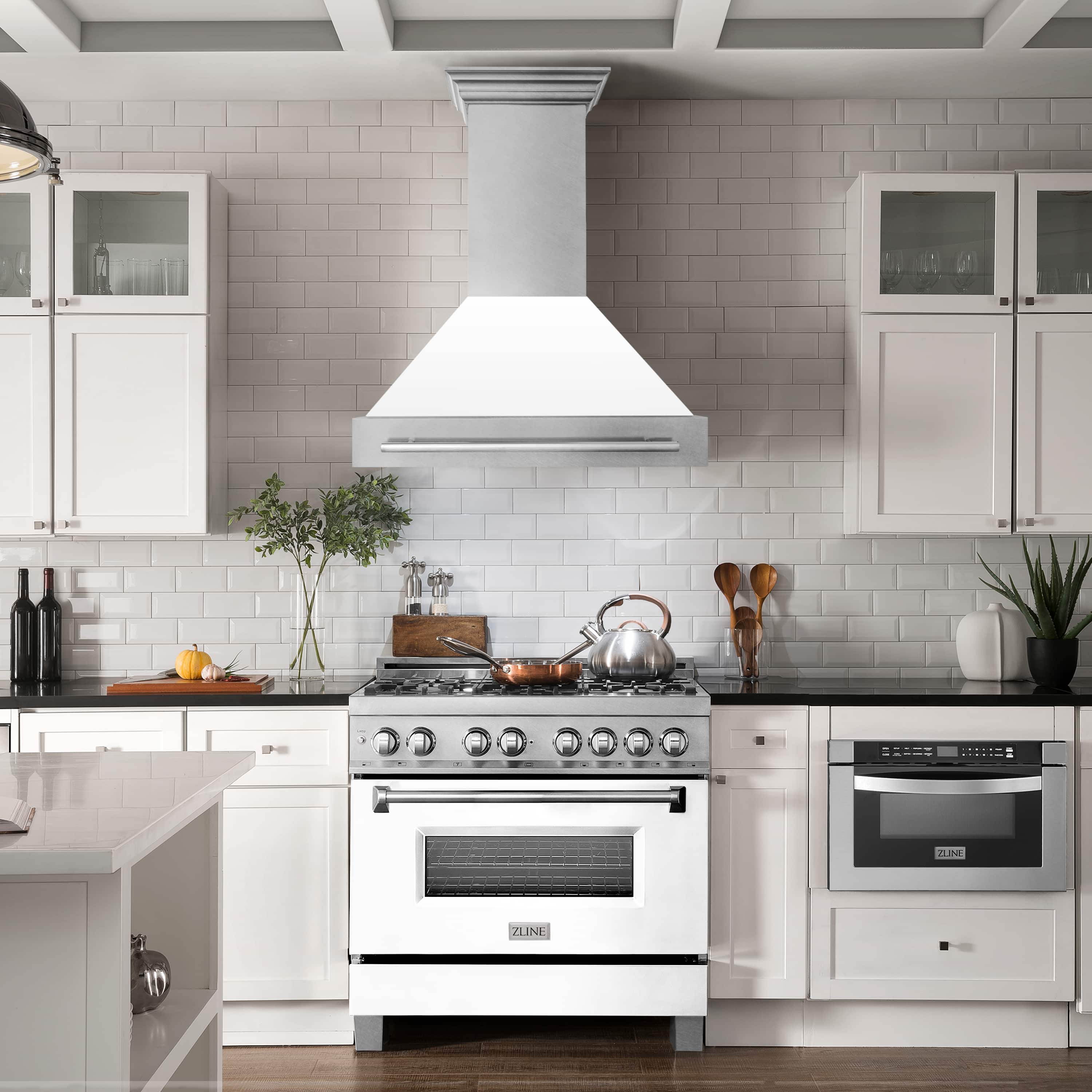 Wall mount range hood centered over a kitchen stove, white matte chimney and stainless hood