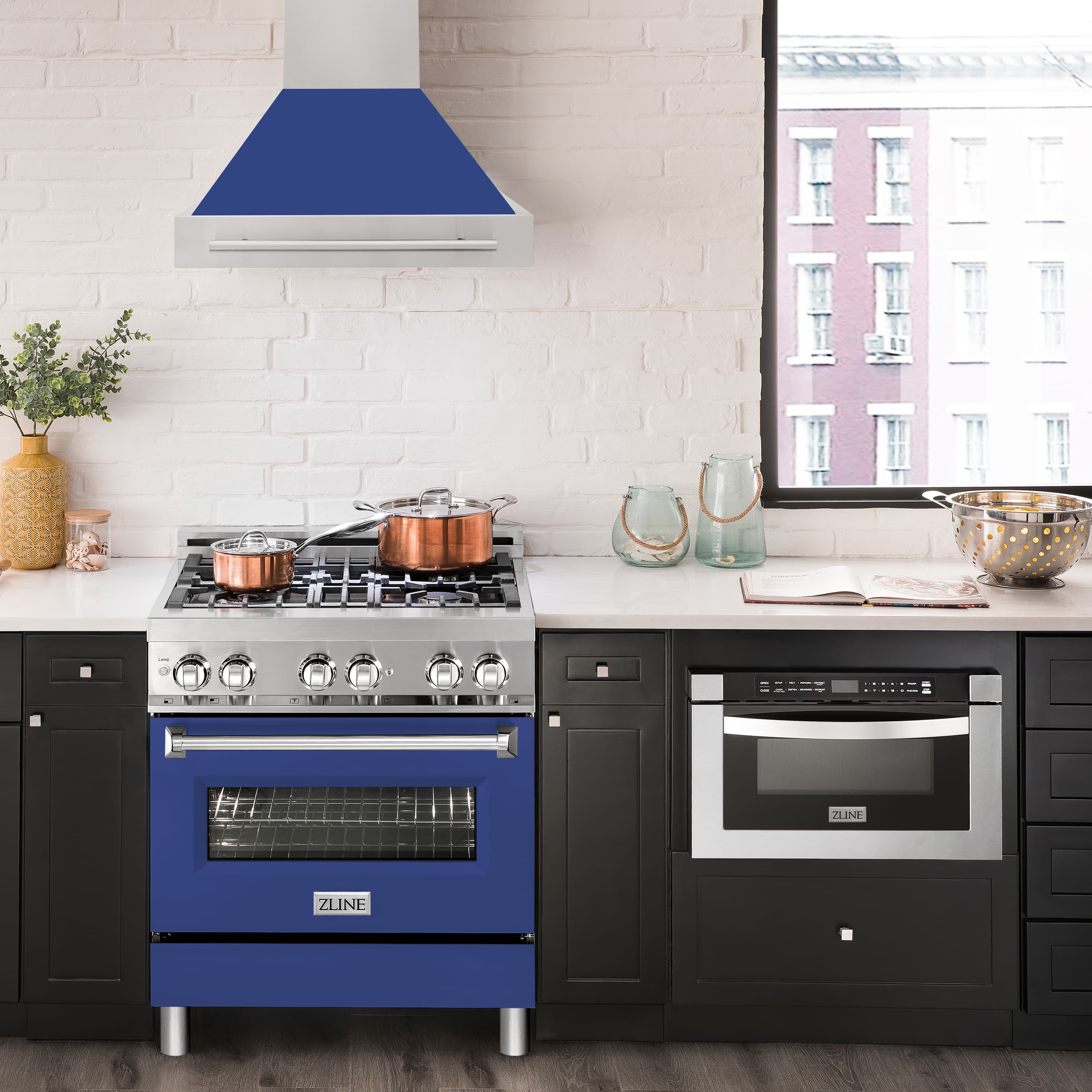 Stainless steel and blue matte wall mount range hood above a black gas range with built-in controls