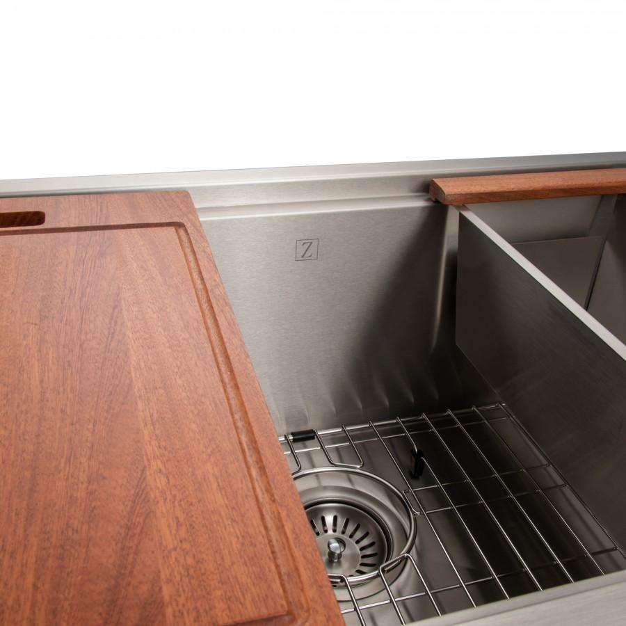 Close-up of stainless sink basin with wood board, bottom grid, and drain strainer.
