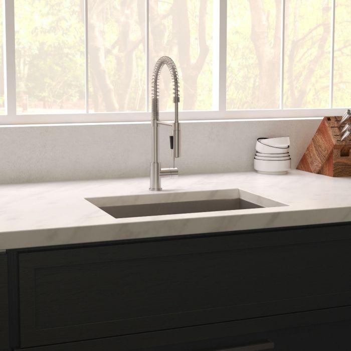 Undermount stainless steel single-bowl sink with central drain strainer installed in countertop