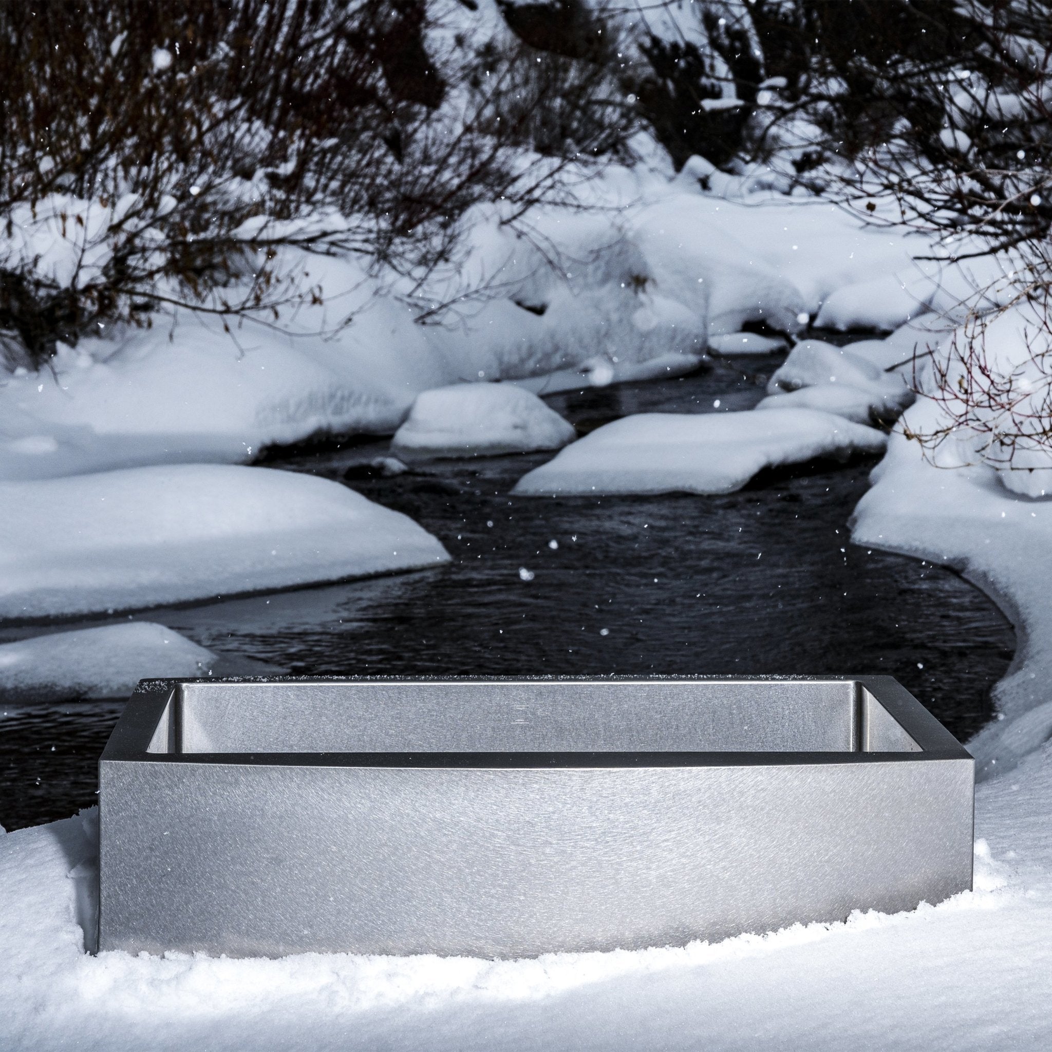 Stainless steel apron-front sink partially covered in snow