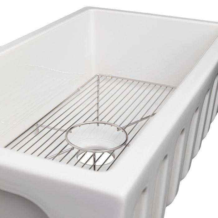 White fireclay single-bowl kitchen sink with bottom grid and circular strainer