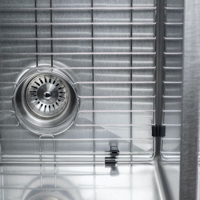Stainless steel sink drain strainer on a bottom grid inside a double bowl