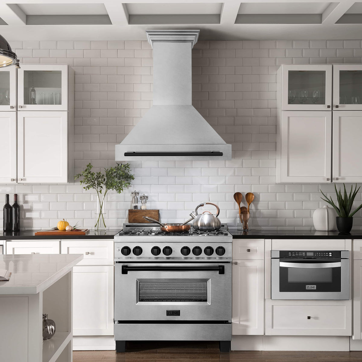 Wall mount range hood over a kitchen stove with satin stainless chimney and black handle