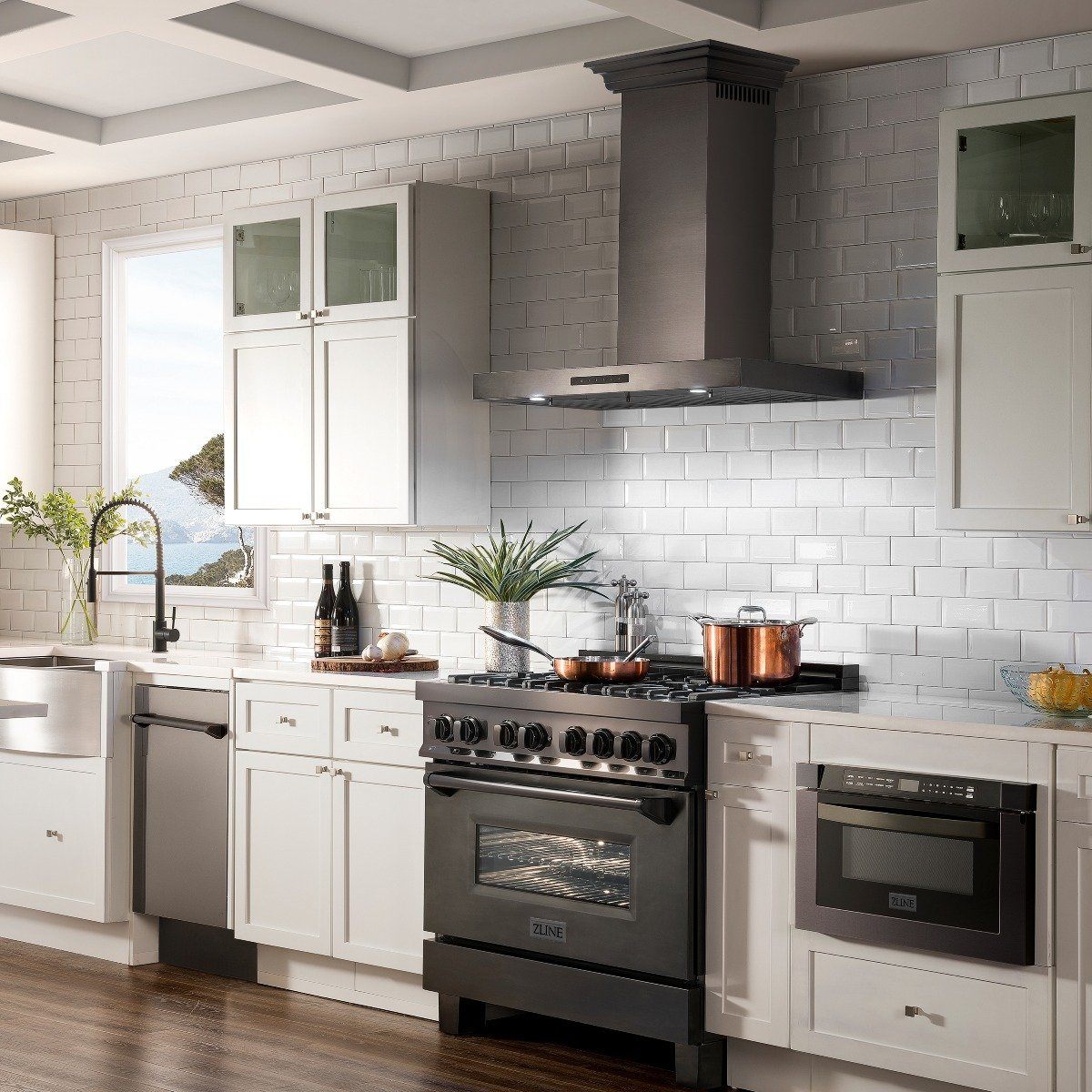 Black stainless range hood over a cooking range in a bright modern kitchen