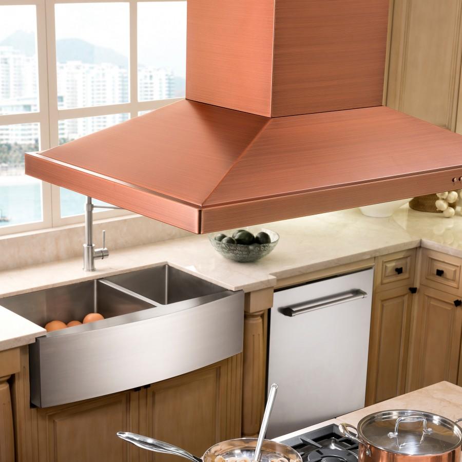 Stainless steel double-basin apron sink under a modern hood, with faucet at left.