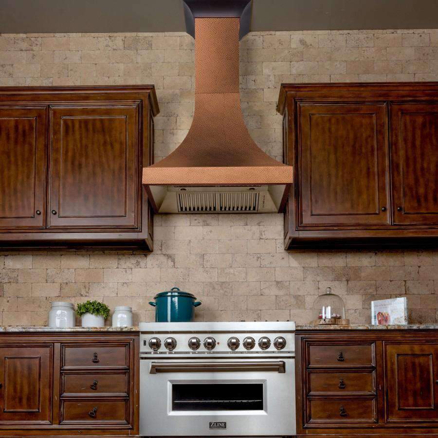 Copper hammered chimney wall range hood with stainless vent canopy under cabinets