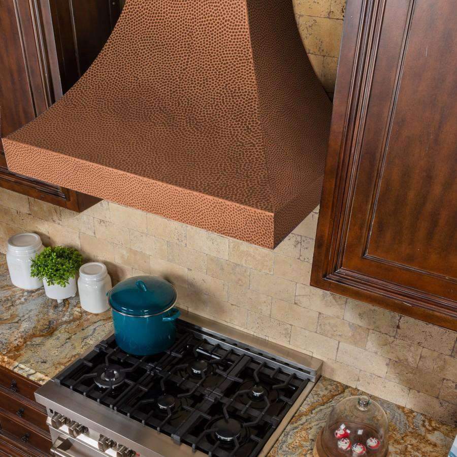 Copper hammered wall range hood with stainless underside vent over gas stove