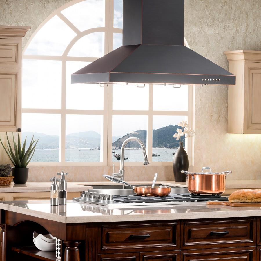 Black island range hood above a stove with copper cookware and sink below