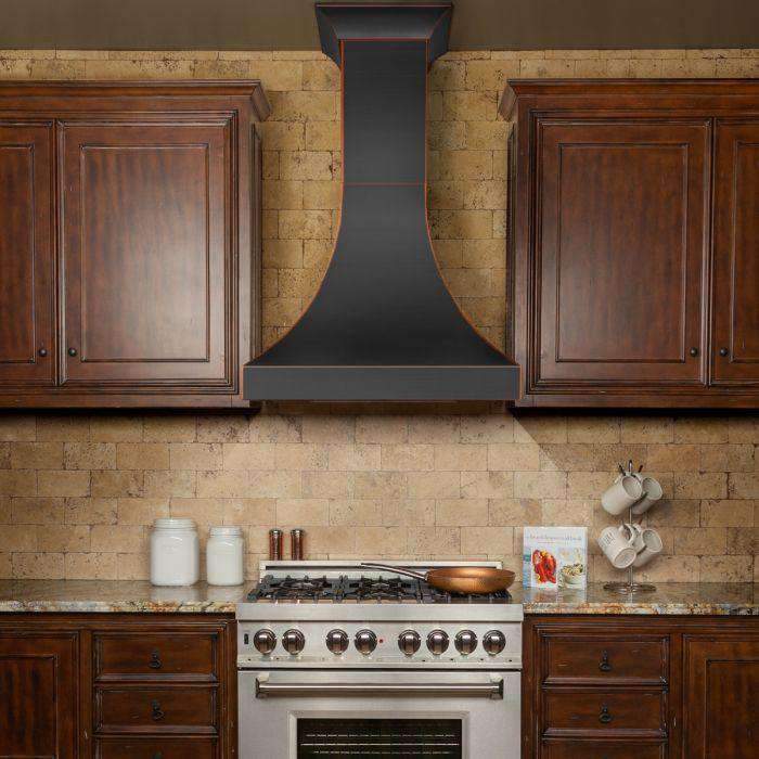 Wall-mount range hood with dark curved chimney and bronze-trim border between cabinets.
