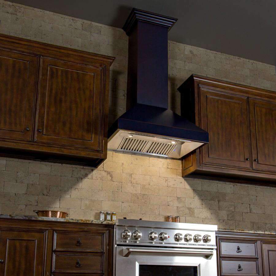 Oil-rubbed bronze wall range hood extending from wood cabinetry