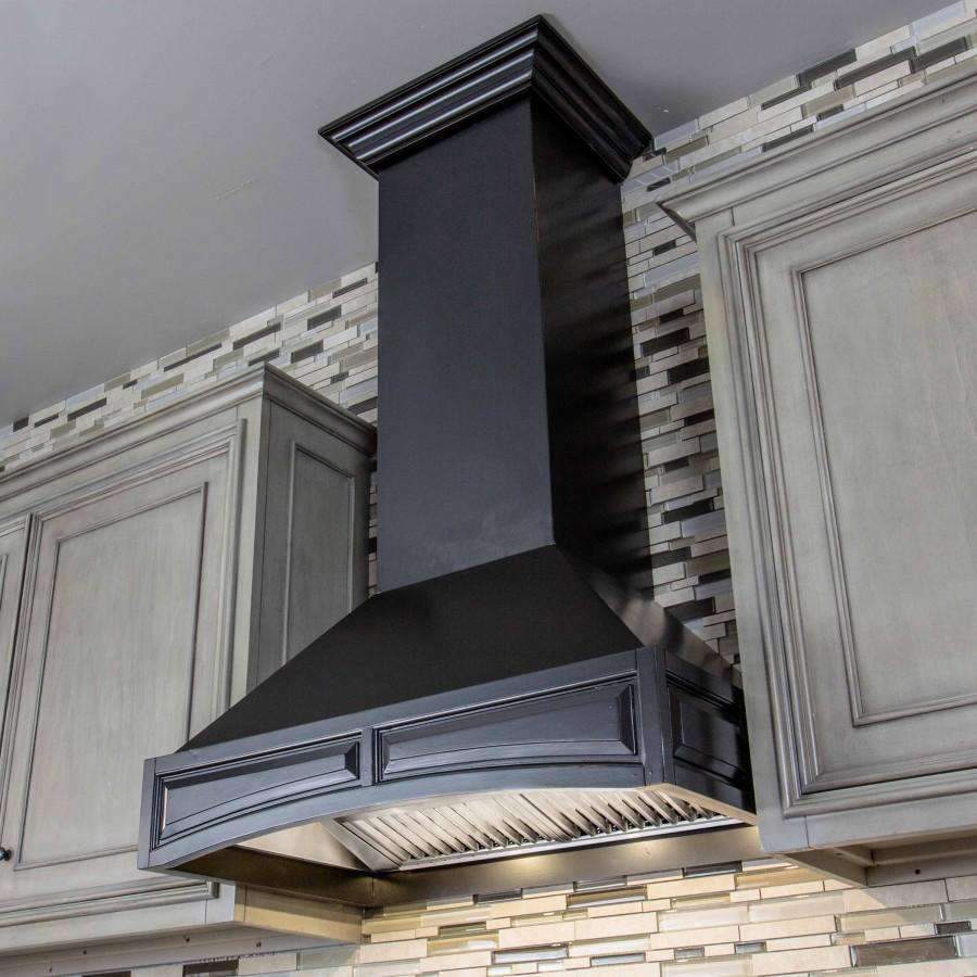 Black chimney wall range hood with crown-style trim and an angled vent grille