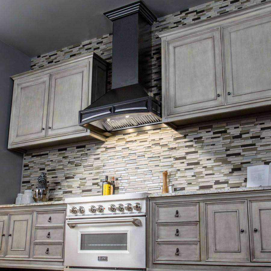 Black wall-mounted range hood above a kitchen range with a stainless vent grille