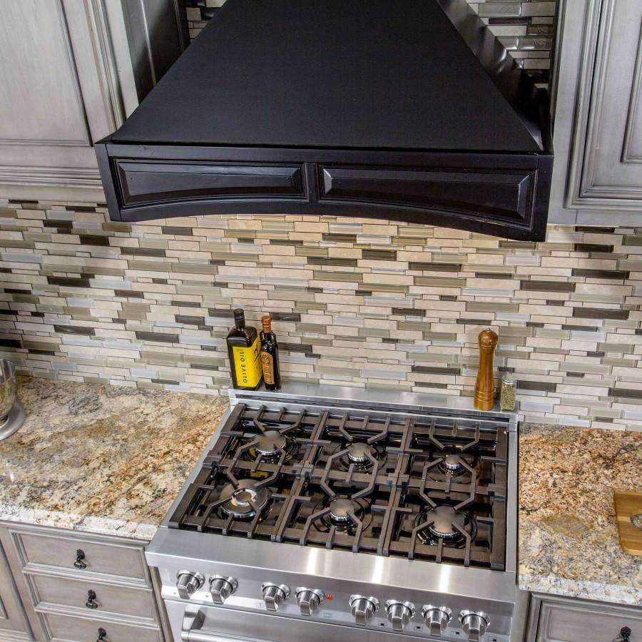 Black range hood underside with vent slots above a gas cooktop and control knobs
