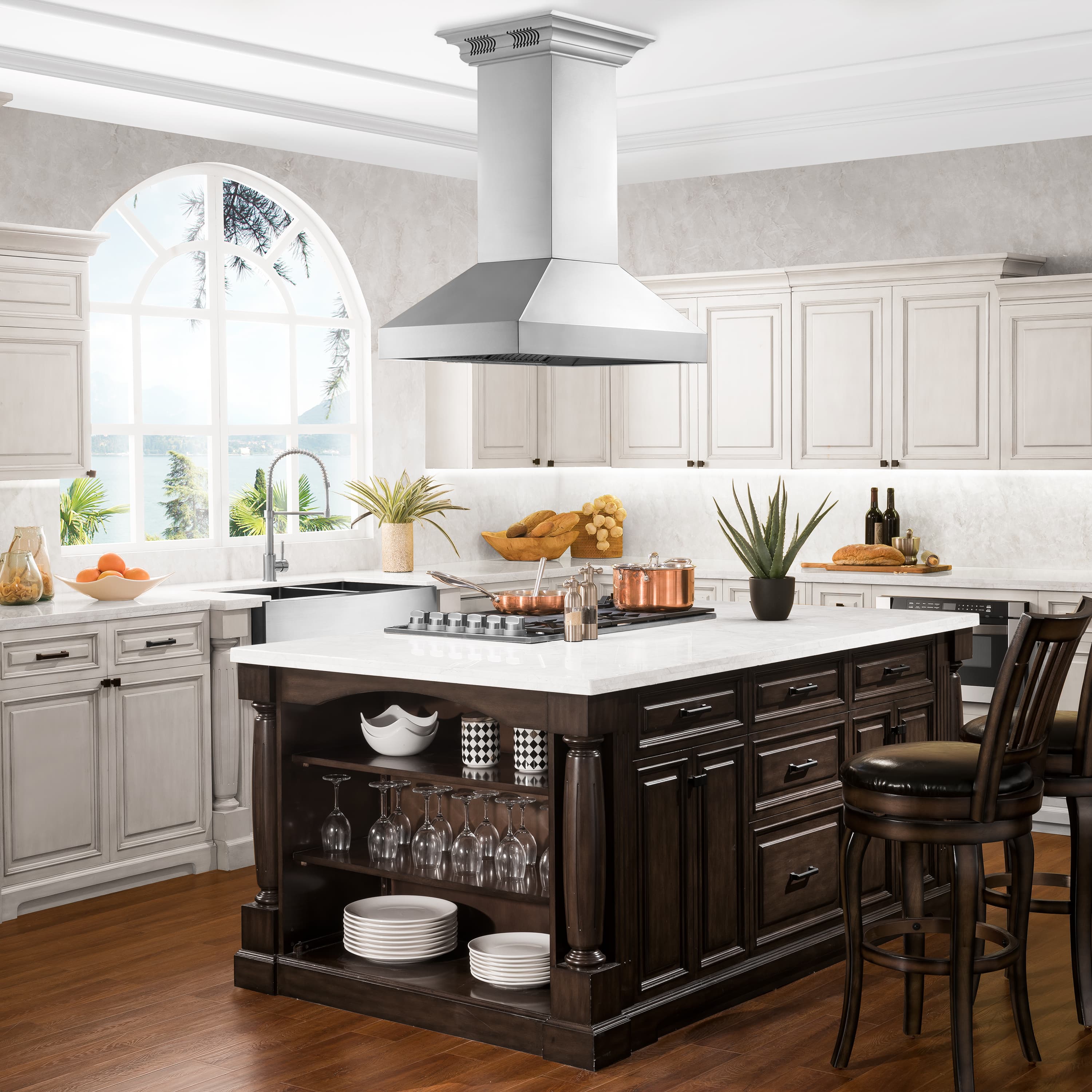 Stainless steel island range hood above a cooktop with chimney-style canopy