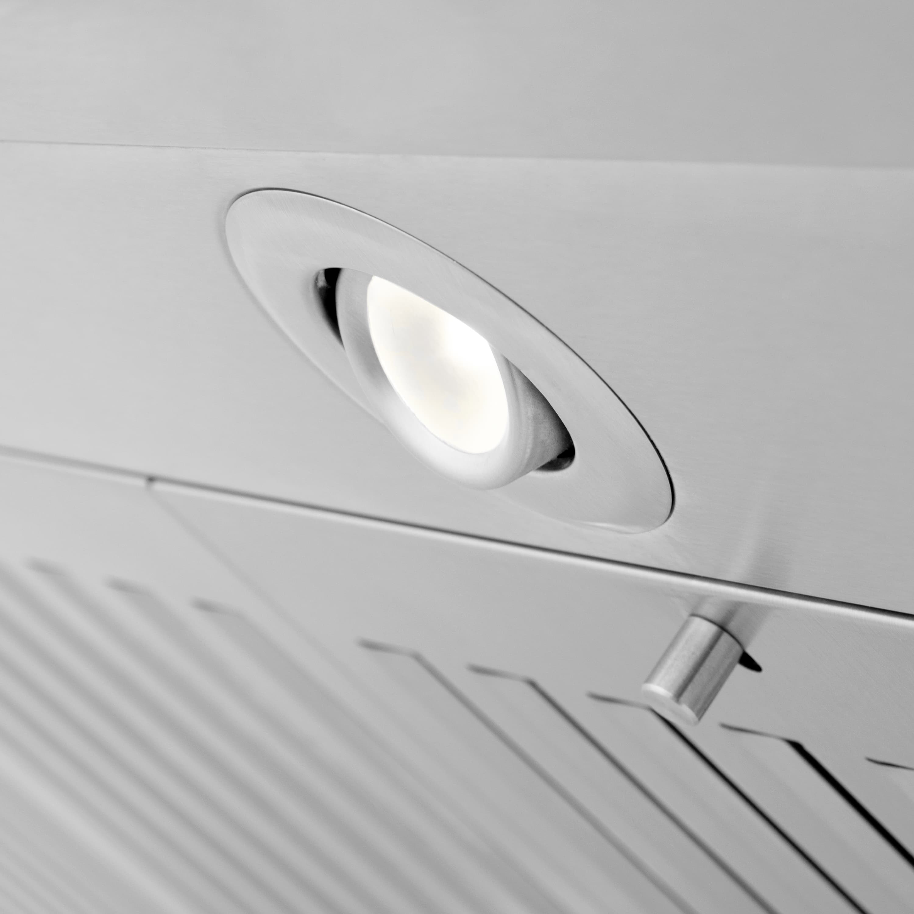 Range hood vent light housing in a circular trim on the stainless steel panel
