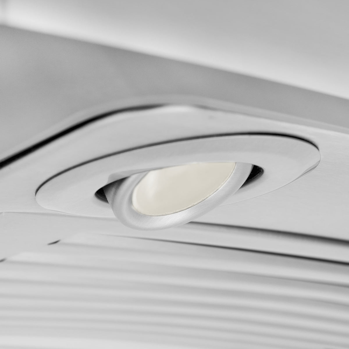 Close-up of recessed light and circular trim on the island range hood canopy