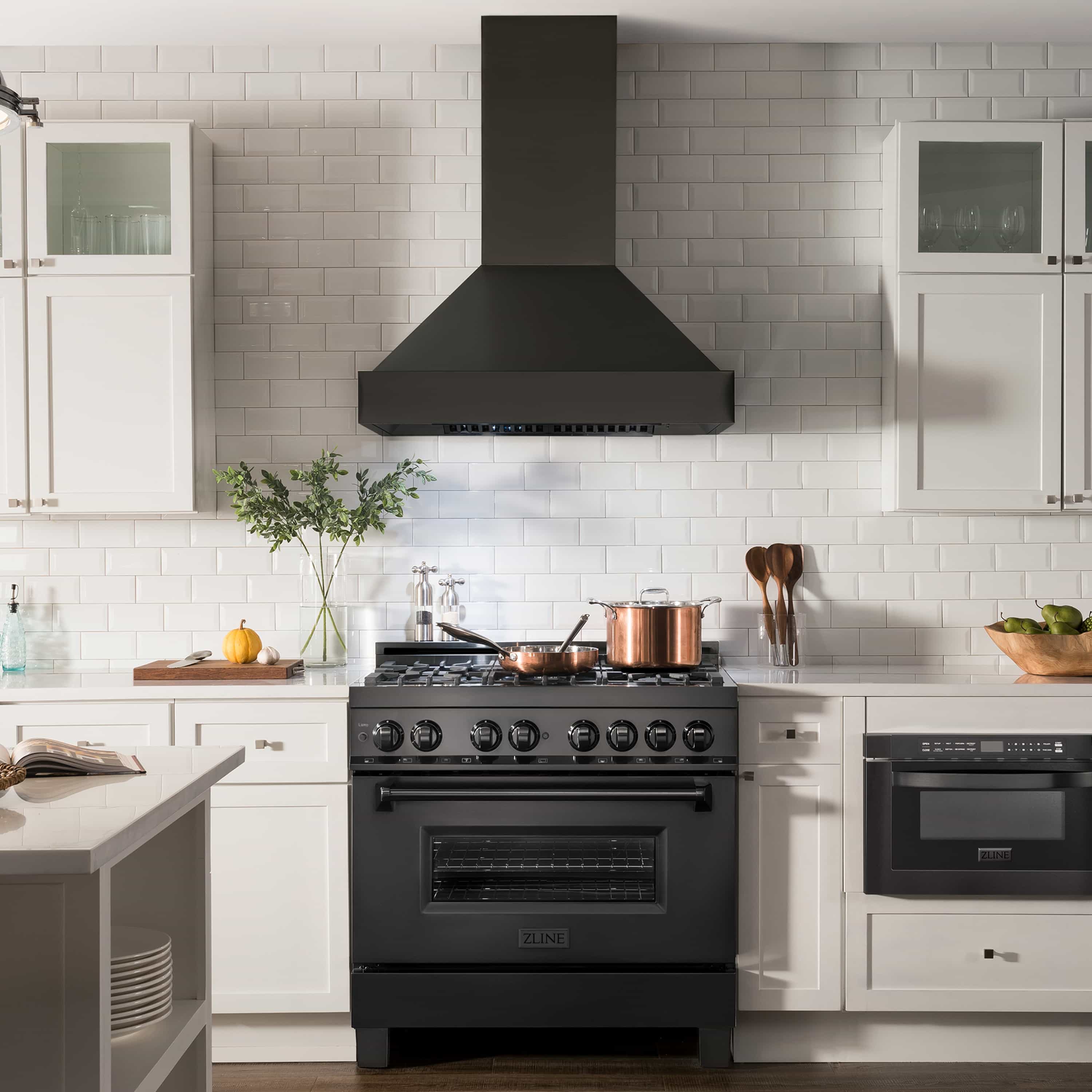 Black wall-mount range hood above a gas range in a bright kitchen