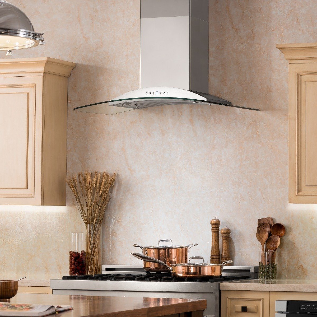 Stainless steel wall mount range hood with glass-edged canopy above a cooktop