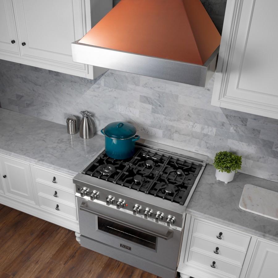 Wall mount range hood with copper hood panel and stainless steel vent above cooktop