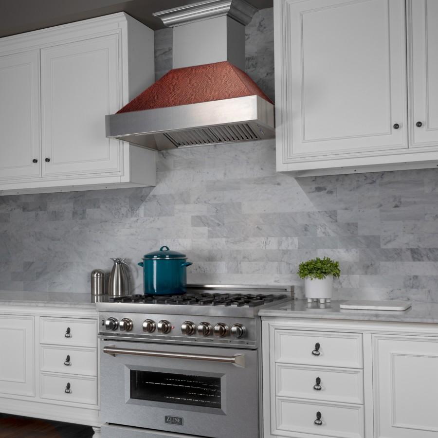 Ducted wall range hood over gas cooktop with stainless chimney and copper hood insert
