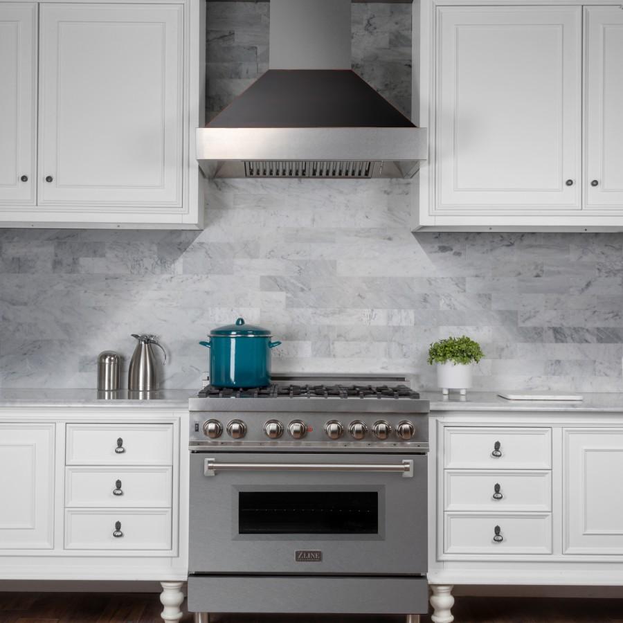 Wall mount ducted range hood with stainless steel body and black canopy above stove