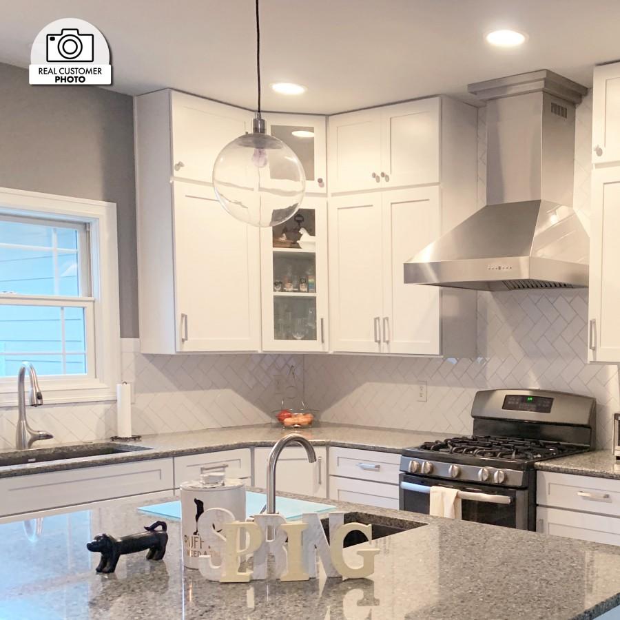 Stainless steel ducted wall mount range hood above the stove in a home kitchen