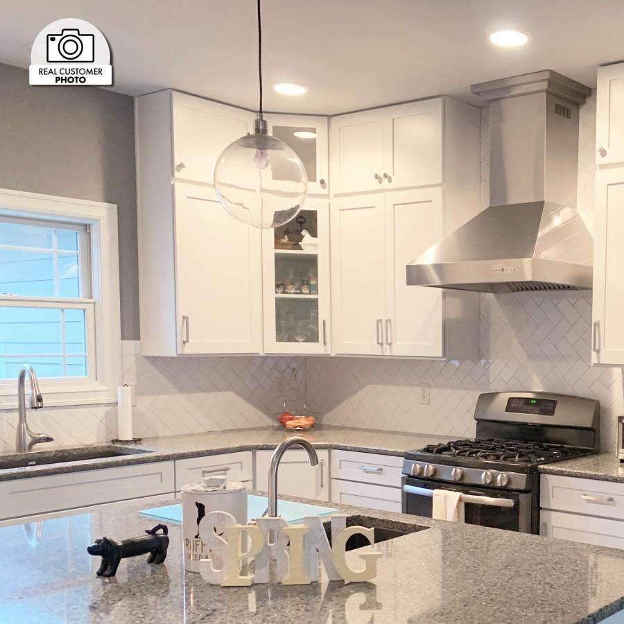 Stainless steel ducted wall mount range hood above stove in a home kitchen