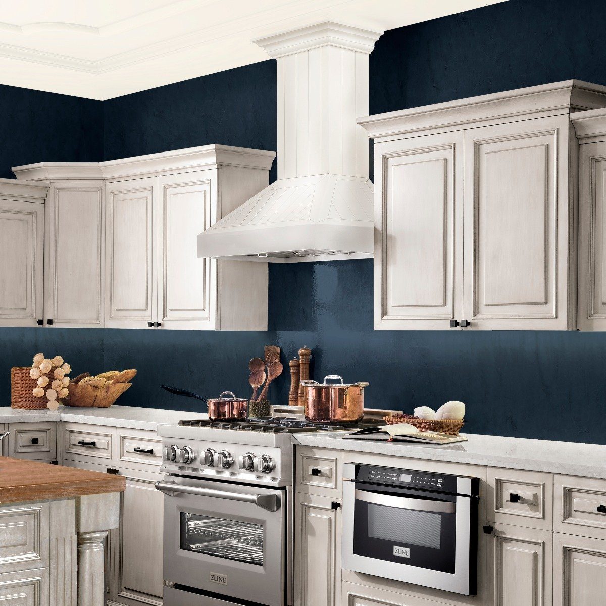 Cottage white wooden wall mount range hood above a stainless gas stove