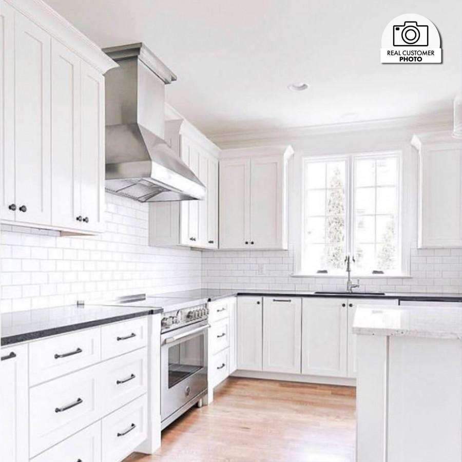Stainless steel wall-mount range hood with crown molding, installed over cooktop