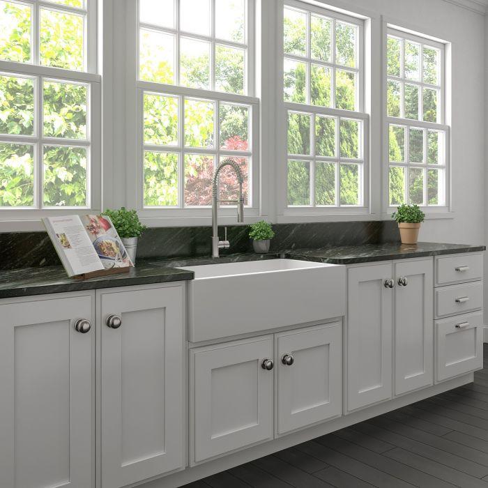 White matte farmhouse fireclay sink with built-in faucet and stainless bottom grid