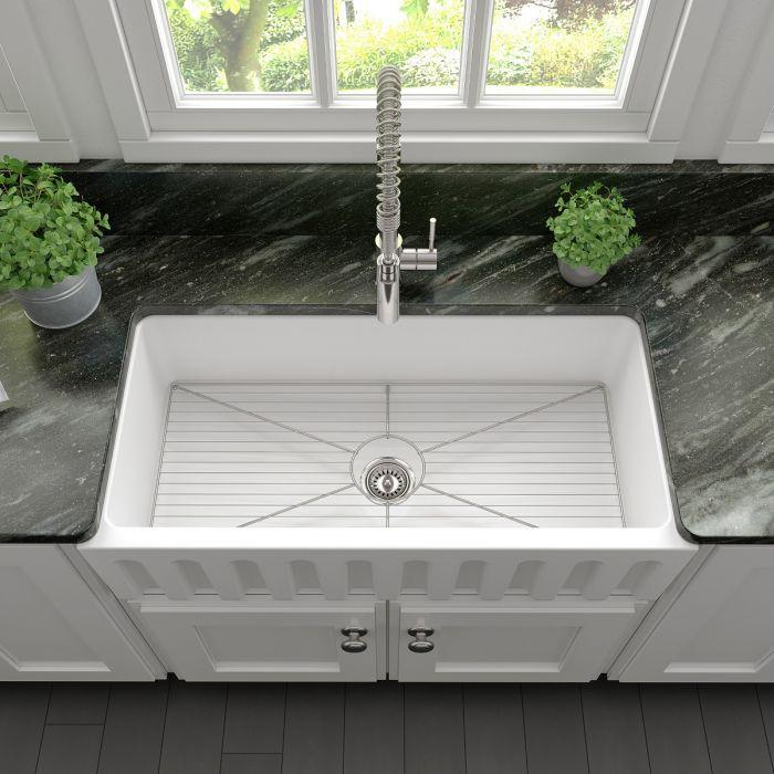 White matte farmhouse fireclay sink basin with stainless bottom grid and drain
