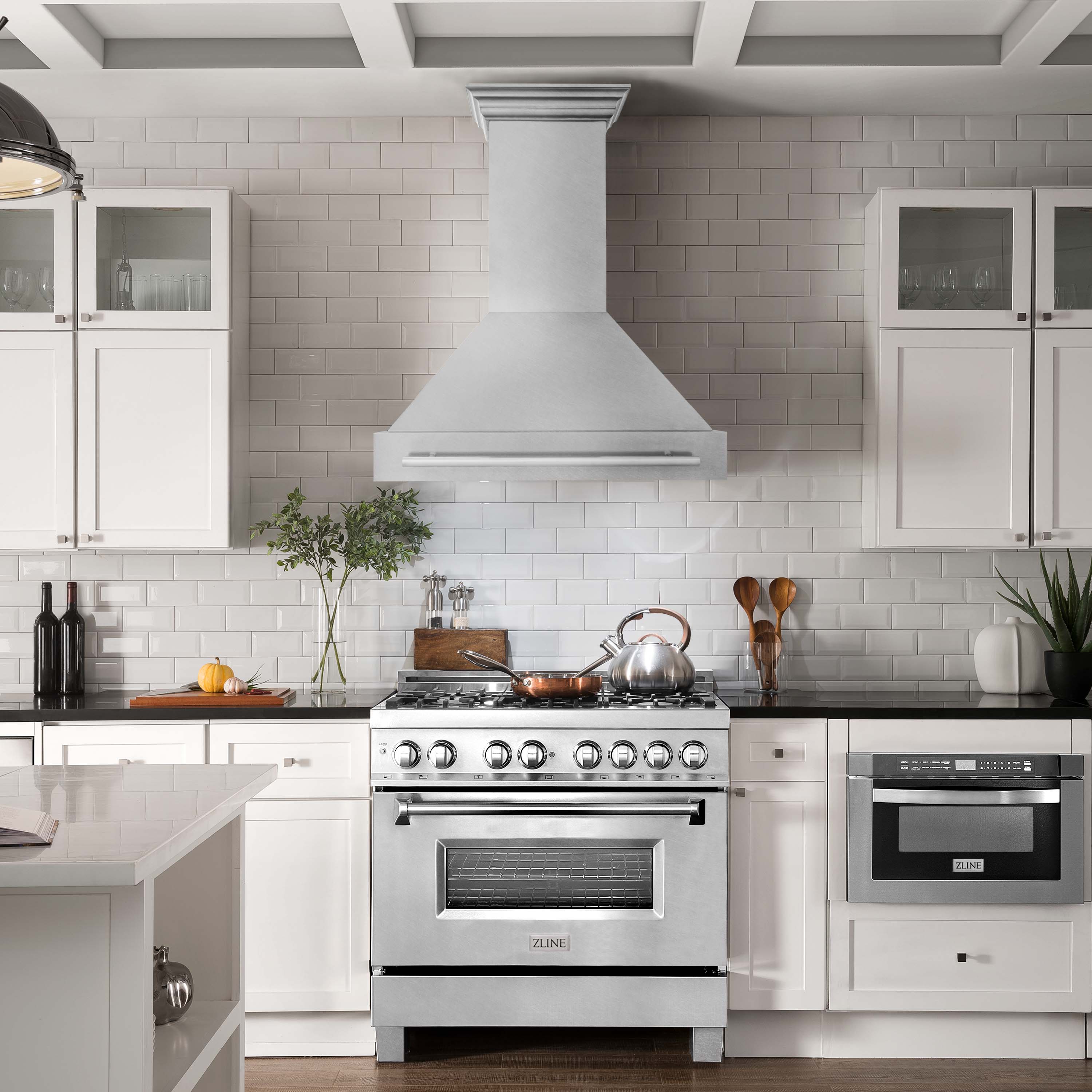 Satin stainless steel wall-mount range hood above a cooktop with chimney chimney