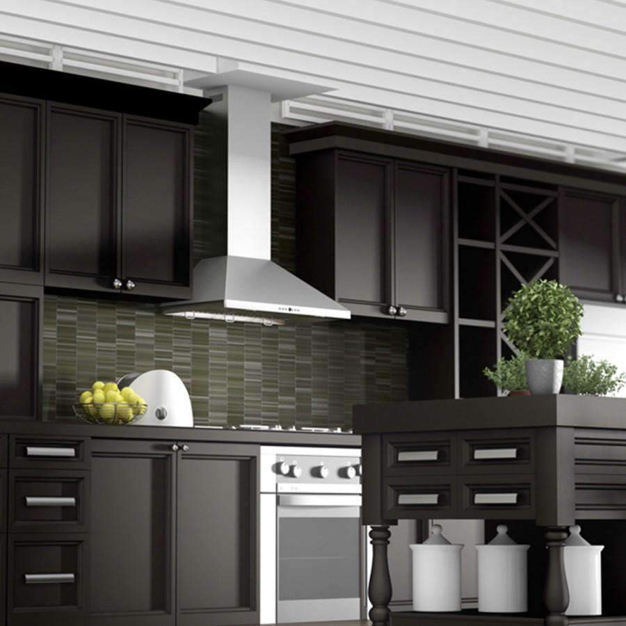 Stainless steel wall chimney range hood installed above cooktop between cabinets