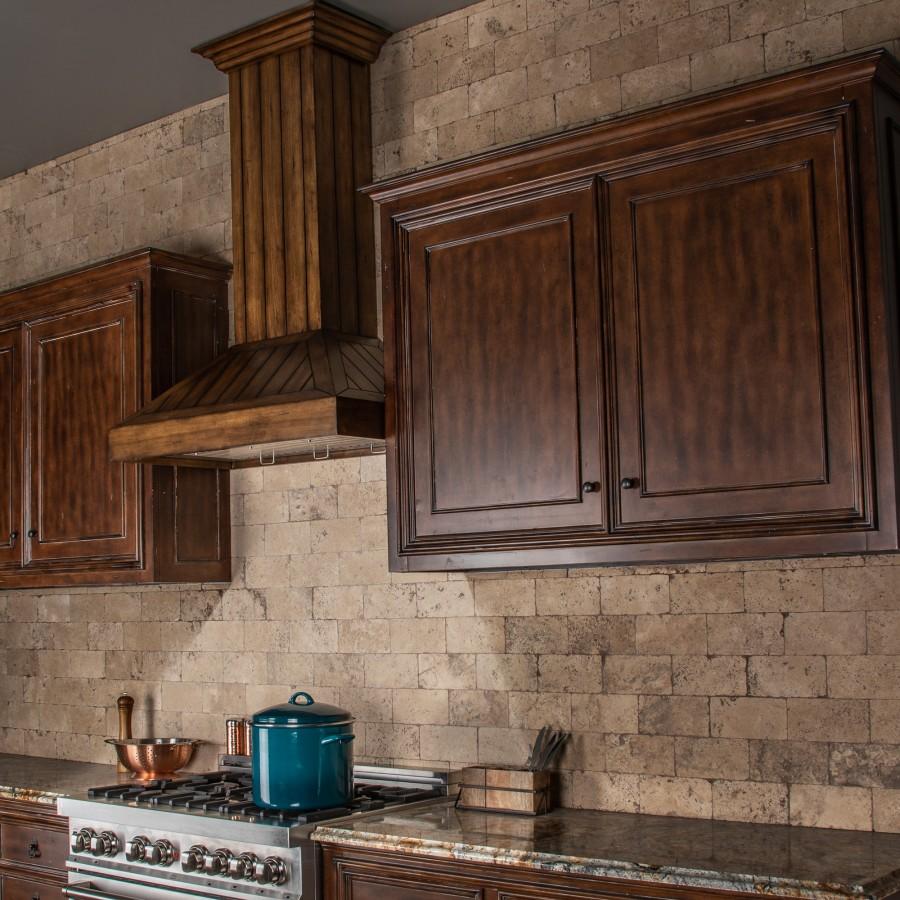 Rustic wooden wall range hood vent over a stove beside dark wooden cabinets