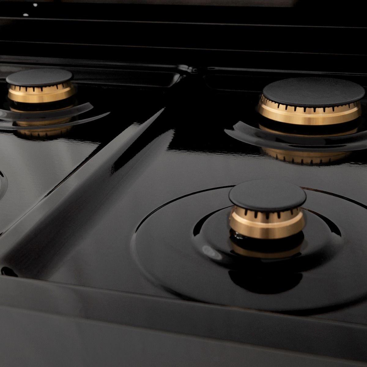 Black dual fuel cooktop with brass burner rings and control knob caps
