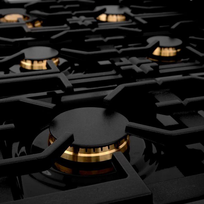 Gas cooktop burners with brass-colored caps on black grates